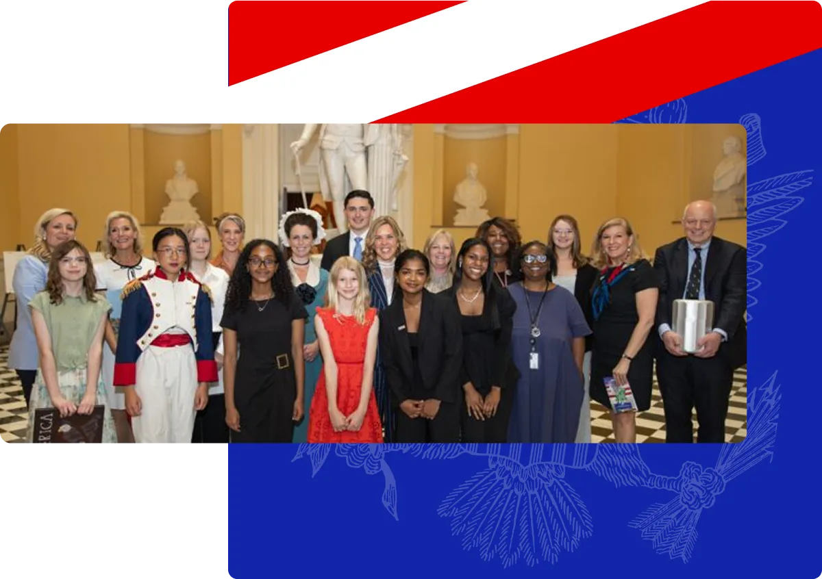 A diverse group of people posing indoors with a statue and busts in the background on a checkered floor.
