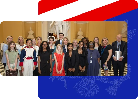 A diverse group of people posing indoors with a statue and busts in the background on a checkered floor.